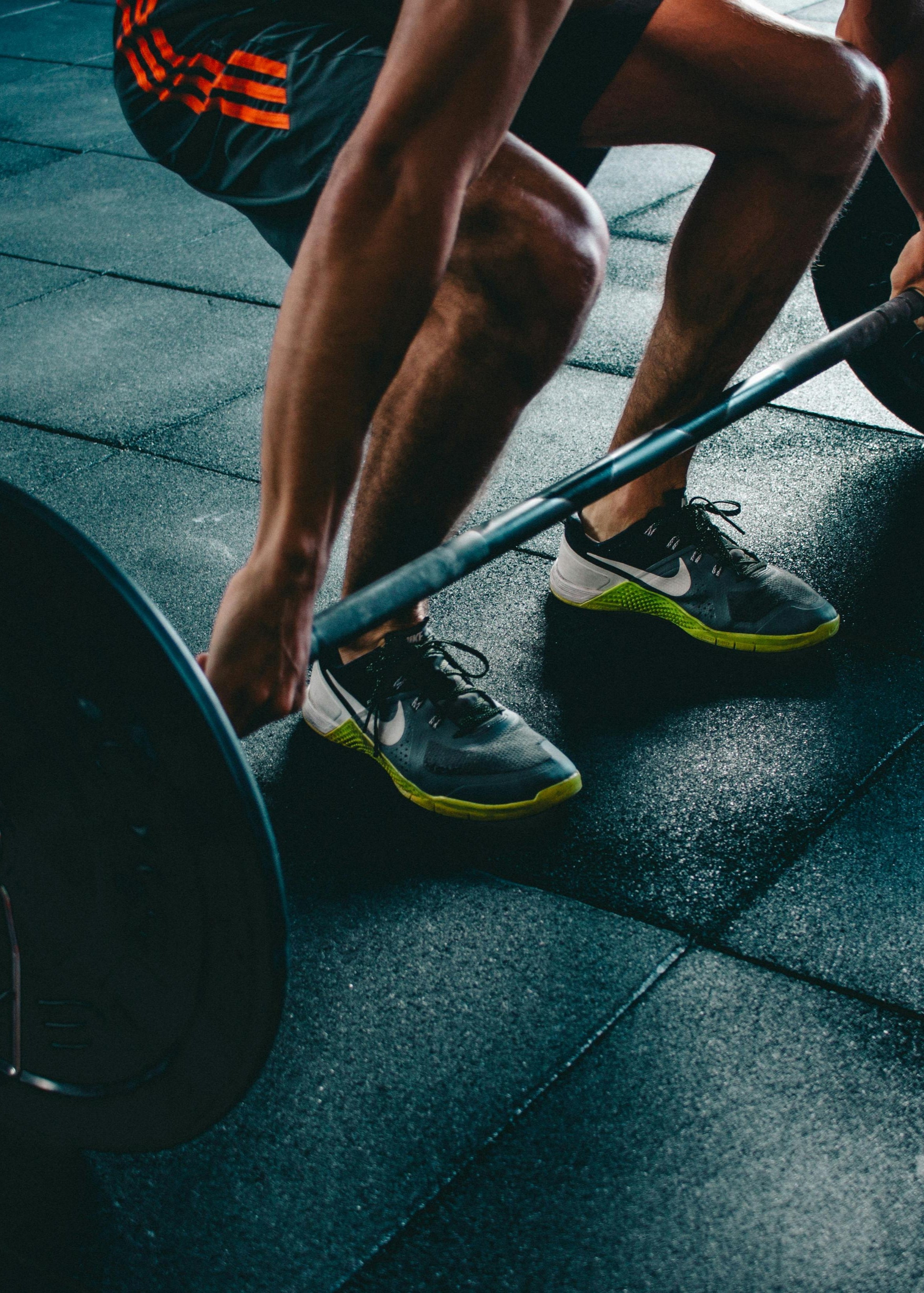 Person lifting a barbell on a tiled floor